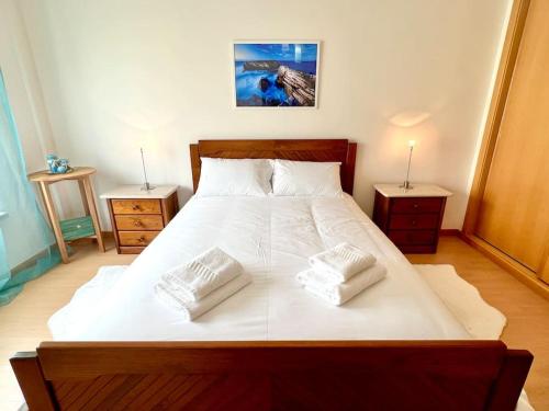 um quarto com uma grande cama branca com duas mesas de cabeceira em Appartement T2 avec vue panoramique sur la côte em Atouguia da Baleia