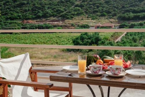a table with a bowl of fruit and glasses of orange juice at Drita Studios & Apartments in Svoronata