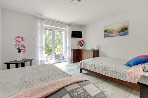 ein weißes Schlafzimmer mit 2 Betten und einem Fenster in der Unterkunft POKOJE GOŚCINNE LAWENDOWY DWÓR in Mikoszewo