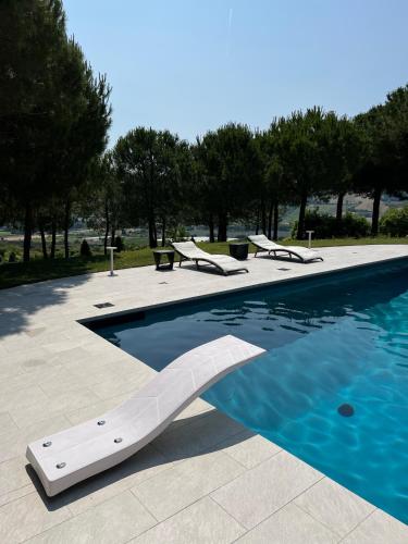 a swimming pool with chairs and blue water at GreenValley BnB in Lapedona