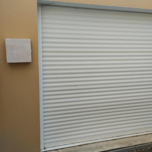 a white garage door on the side of a building at Studio attenant a la maison principale in Saint-Martin-des-Tilleuls