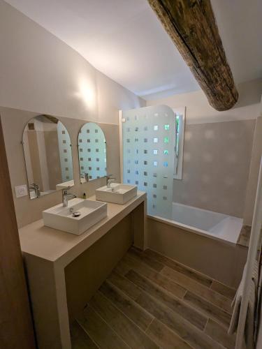 une salle de bain avec deux lavabos, un miroir et une baignoire dans l'établissement La ferme du TourreBlanc, à Lambesc
