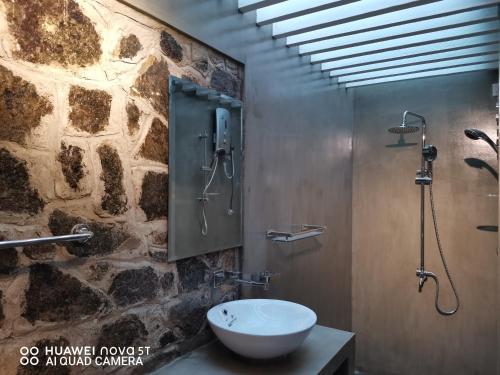 a bathroom with a sink and a stone wall at Bee Cottage Negombo in Negombo