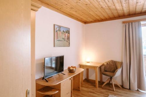 a living room with a television and a desk at Feichtingerhof in Steinbach am Attersee