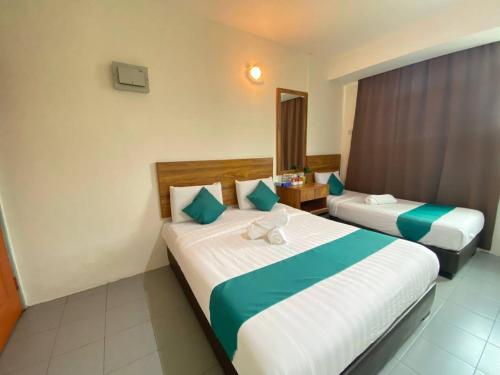 a hotel room with two beds and a mirror at Sun Tree Hotel in Kampong Kerayong
