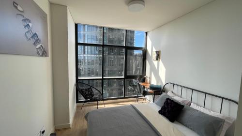 a bedroom with a bed and a large window at Wentworth Point Oversized balcony view apartment in Sydney