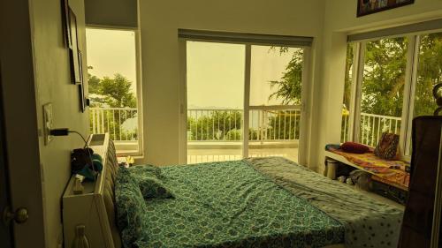 a bedroom with a bed in a room with windows at Mayur Home Stay, Morni Hills in Morni