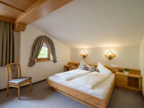 a bedroom with a large bed and a chair at Landhaus Casper in Gerlos