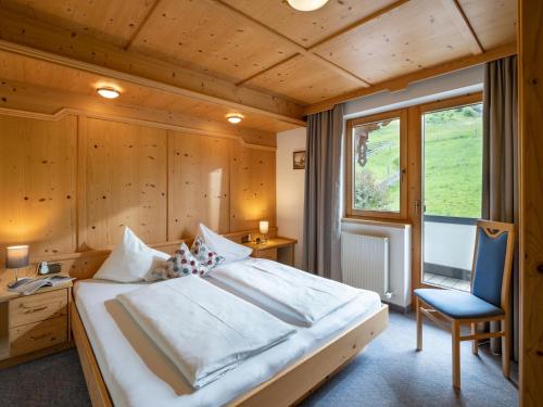 a bedroom with a large bed and a blue chair at Landhaus Casper in Gerlos