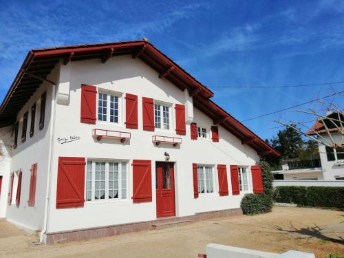 a white and red house with red shutters at Maison au coeur d’Arcangues, proximité de Biarritz in Arcangues