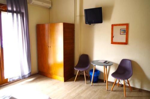 Zimmer mit 2 Stühlen, einem Tisch und einem TV in der Unterkunft Sotiras Rooms in Skala Sotiros