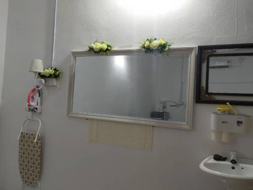 a bathroom with a mirror and a sink with flowers on it at Rumah Tamu FieSari Jeli M U S L I M in Jeli