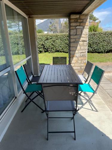 une table et des chaises assises sur une terrasse couverte dans l'établissement À deux pas de la plage du Fogeo Arzon, à Arzon