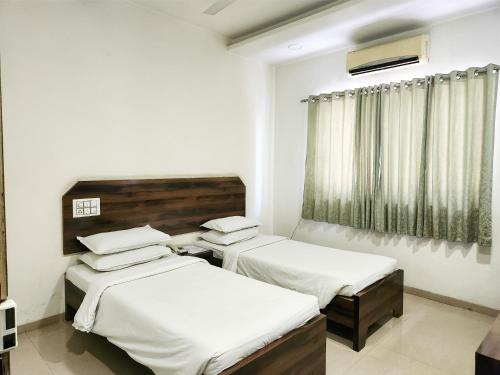 1 dormitorio con 2 camas y ventana en Hotel Rajwada Aurangabad, en Aurangabad