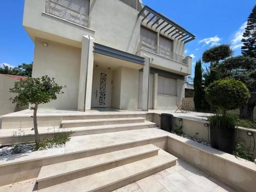 une maison blanche avec des escaliers en face de celle-ci dans l'établissement Kosher Luxury villa - Raanana, à Ra‘ananna