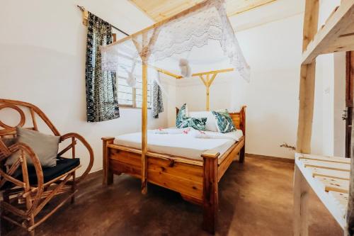 キウェンワにあるThe Kichwa Houseのベッドルーム(天蓋付きベッド1台、椅子付)