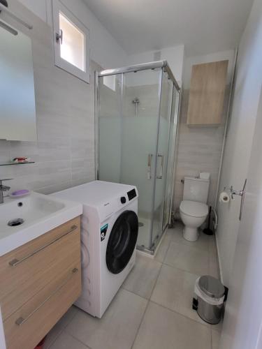 une salle de bain avec machine à laver et toilettes dans l'établissement Plage Studio 5 personnes St cyprien 66750, à Saint-Cyprien