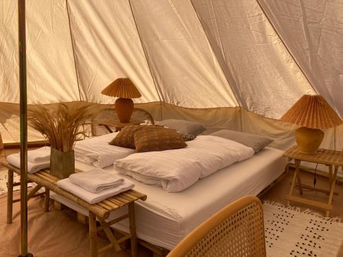 - un lit dans une tente avec 2 chaises et des lampes dans l'établissement Bådsted Camping, à Gudhjem