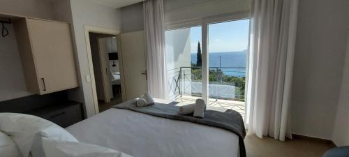 a bedroom with a bed and a large window at Les Maisonettes in Kokkari