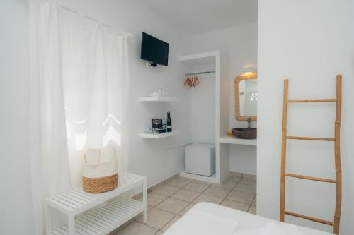 a bathroom with white walls and a mirror and a shelf at Nostos Sifnos in Apollonia