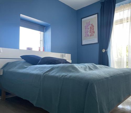 a blue bedroom with a bed with a blue wall at Havudsigt, skøn lille lejlighed in Tranekær