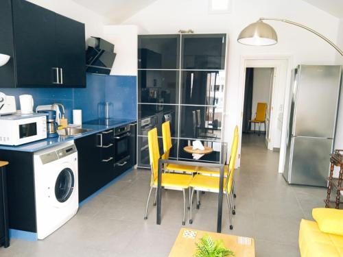 een keuken met blauwe kasten en een tafel met gele stoelen bij CANARY Beach I in Costa Teguise