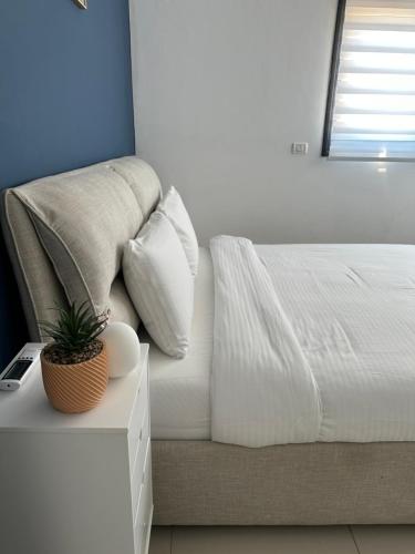 a bedroom with a bed with a plant on a night stand at Sea view penthouse Private rooftop jacuzzi in Eilat