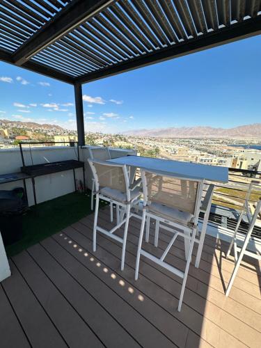 a table and chairs on a deck with a view at Sea view penthouse Private rooftop jacuzzi in Eilat