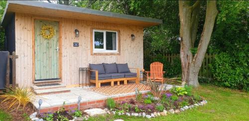 um barracão com um sofá e uma cadeira num quintal em LILAC COTTAGE cabin em Swafield