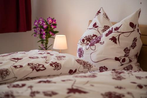 - un lit avec des draps blancs et un vase de fleurs dans l'établissement Ferienwohnung Attelblick, 