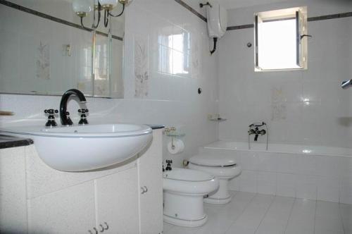 a white bathroom with a sink and a toilet and a tub at Appartamenti Miramare in Collina in Ischia