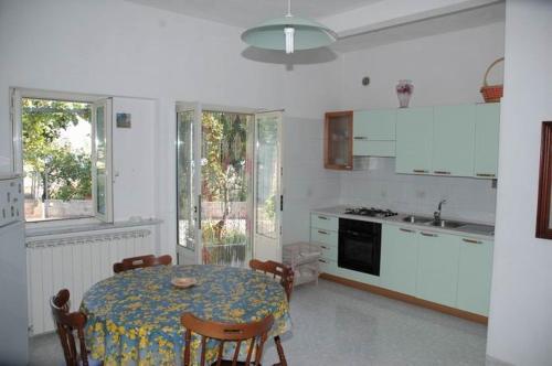 a kitchen with a table and chairs and a kitchen with white cabinets at Appartamenti Miramare in Collina in Ischia