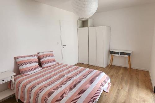een witte slaapkamer met een bed en een nachtkastje bij Jolie demeure à proximité de La Rochelle in La Jarrie