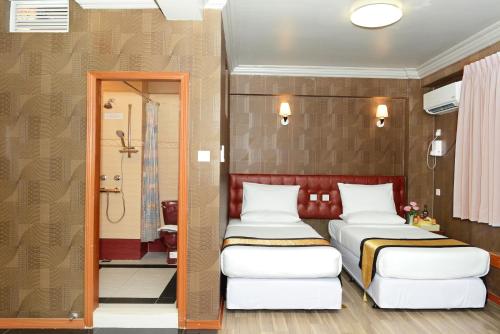 a hotel room with two beds and a shower at Hotel Grand United - Chinatown in Yangon