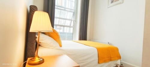 a bedroom with a bed with a lamp and a window at Lovely Beautiful Apartment in Marble Arch in London