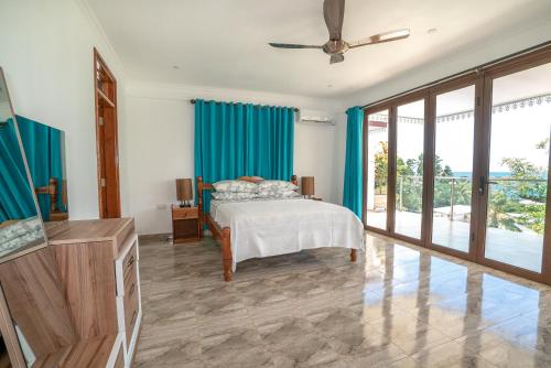 a bedroom with a bed with blue curtains at La Belle Residence Self Catering Accommodation in Beau Vallon