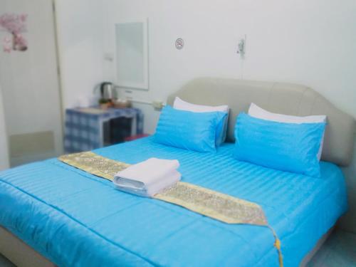 a blue bed with blue pillows and a tray on it at Happy Home Guest House in Ban Phe