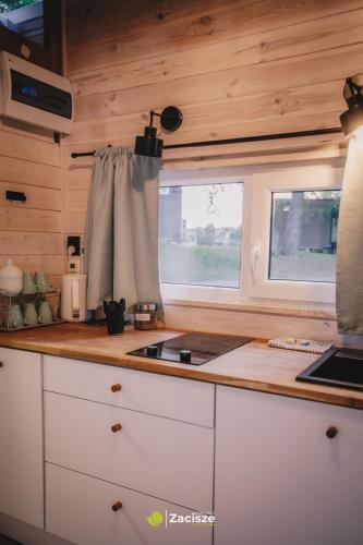 a kitchen with white cabinets and a window at Półwysep Zacisze - Tiny House Village in Przywidz