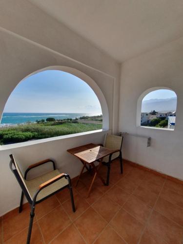 a table and chairs in a room with two windows at Babis & Popi Rooms and Studios in Frangokastello