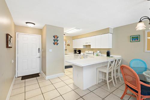 a kitchen with white cabinets and a table and chairs at Seaside Beach & Racquet 2105 in Orange Beach