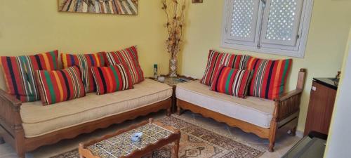 a living room with two couches with colorful pillows at Chambre d'hôtes, Dar l'air du temps in Aghīr