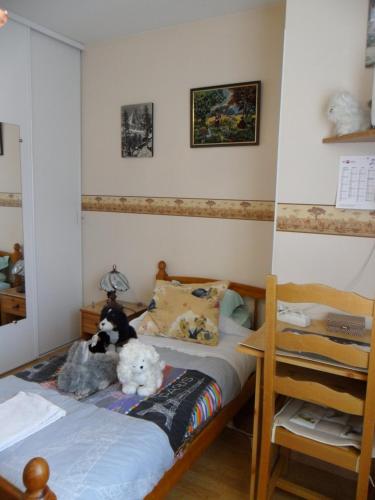 un dormitorio con una cama con dos animales de peluche en Chambre chez l'habitant en Louvres