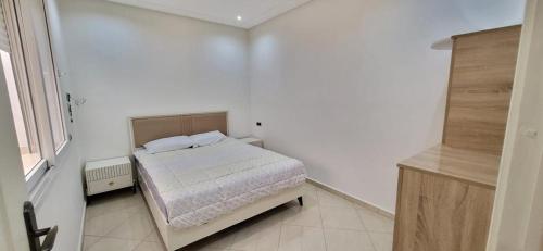 een witte slaapkamer met een bed en een raam bij Agadir chez Omar in Agadir