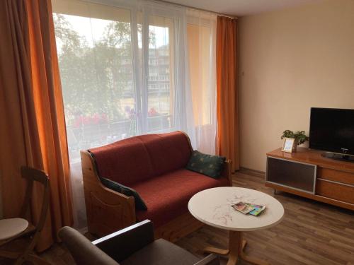 sala de estar con sofá, TV y mesa en Bright & Fresh Studio Near The Sea, en Liepāja