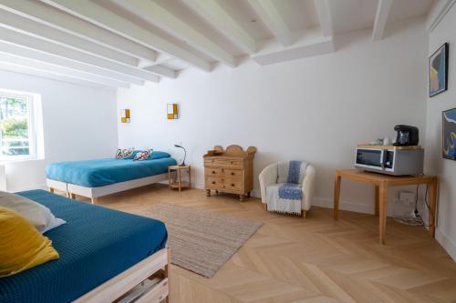 1 Schlafzimmer mit 2 Betten und einem Tisch mit einer Mikrowelle in der Unterkunft La Métairie - Guesthouse in Orx