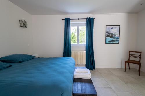 a bedroom with a blue bed and a window at La Métairie - Guesthouse in Orx