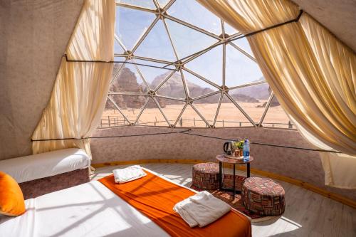 a room with a large window with a bed and a table at Aladdin Camp in Wadi Rum