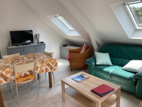 a living room with a green couch and a table at Appartement dans maison de campagne au calme in La Trinité-sur-Mer