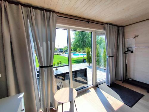 a room with a large window with a view of a yard at Słońce i Woda Domki Całoroczne, Internet Satelitarny STARLINK, Klimatyzacja, Podgrzewany Basen, Bezpłatny Parking in Łeba