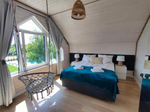 a bedroom with a large bed and a large window at Słońce i Woda Domki Całoroczne, Podgrzewany Basen, Balia z jacuzzi, Starlink Internet, Klimatyzacja, Bezpłatny Parking in Łeba